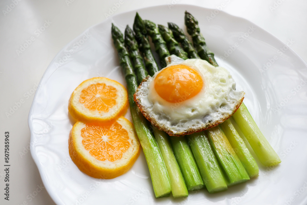 asparagus, lemon and scrambled eggs on a white dish. table setting