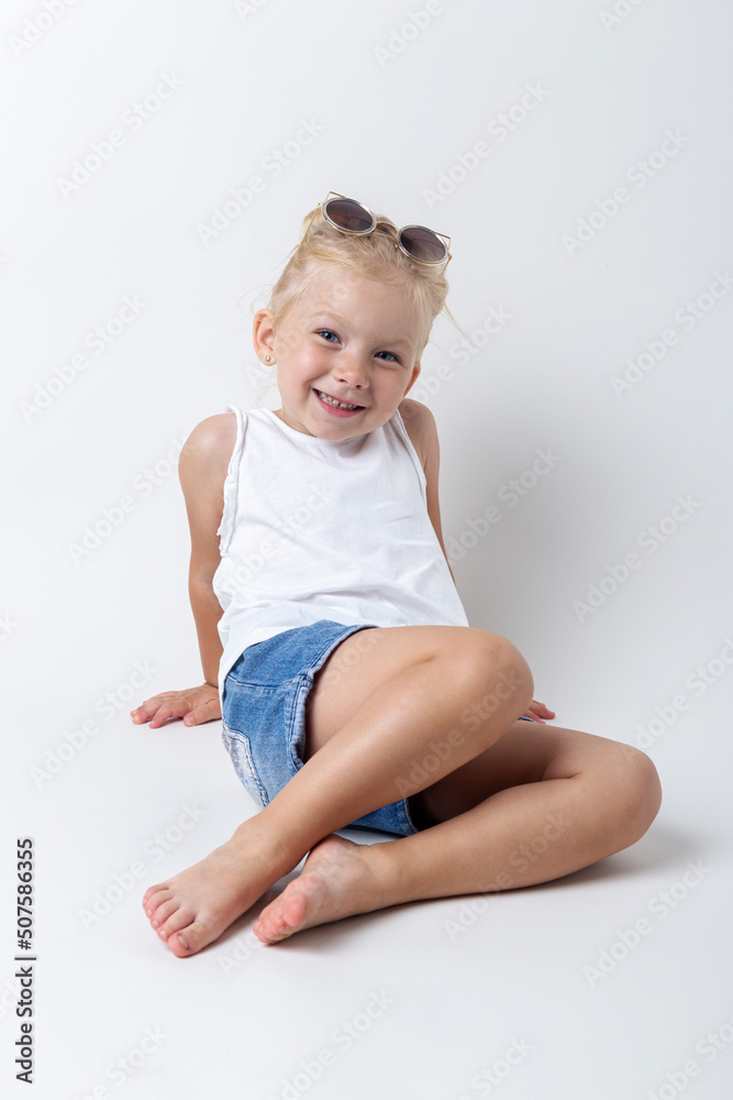 Blond child with sunglasses posing on a light background in the studio Blond child with sunglasses posing on a light background in the studio