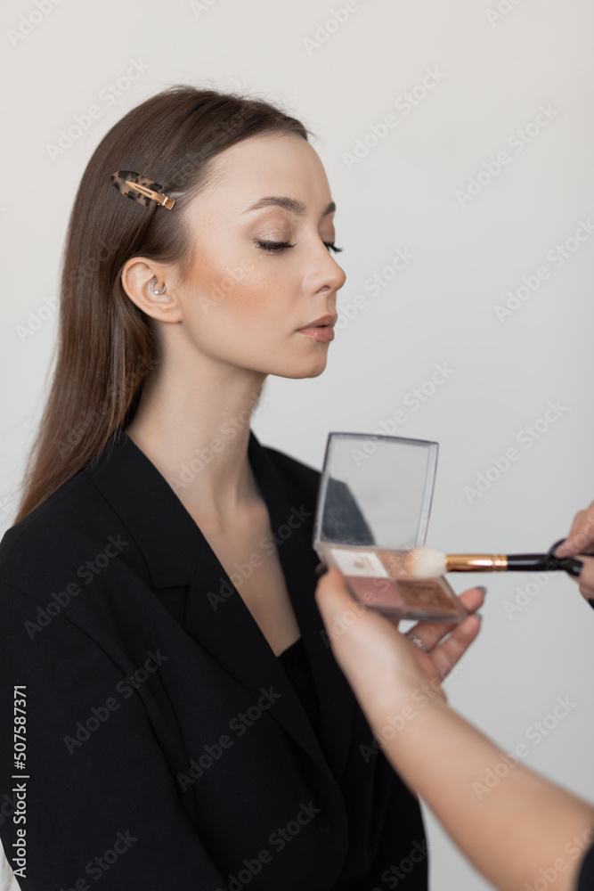 Obraz premium Vertical fashion woman face with close eyes brushing, choose color of nude palette powder and shadows brush. Side view