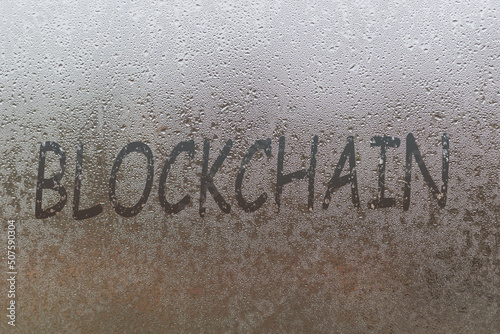 blockchain handwritten on wet glass of night window photo