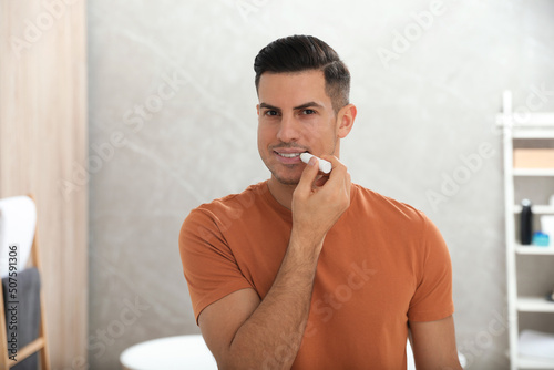 Man applying hygienic lip balm in bathroom