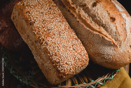 Whole grain breads in a basket. Sesame bread and rye bread close up on a dark rustic background.