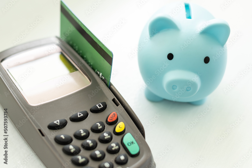 money and savings coins with dollar bills and a payment terminal for cashless payments with a pink piggy bank for savings. money and savings coins with dollar bills and a payment terminal for cashless payments with a pink piggy bank for savings.