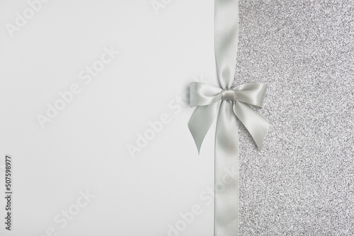 Shiny silver gift ribbon bow on gray background