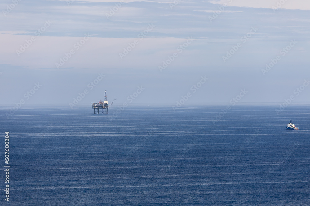 Boat on right delivers shift workers to offshore gas platform in Cantabrian Sea, all shades of blue In this image. Biscay, Basque Country