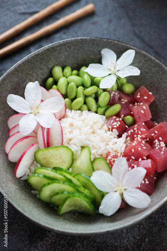 Close-up of hawaiian tuna poke bowl with flowers, vertical shot, selective focus