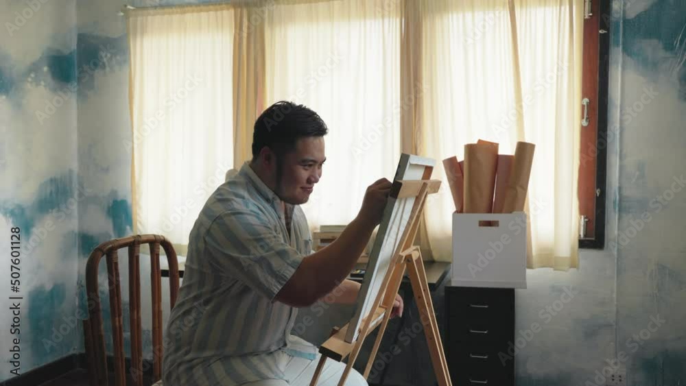 Portrait of a chubby Asian young man happy creating front of canvas Portrait of a chubby Asian young man happy creating front of canvas