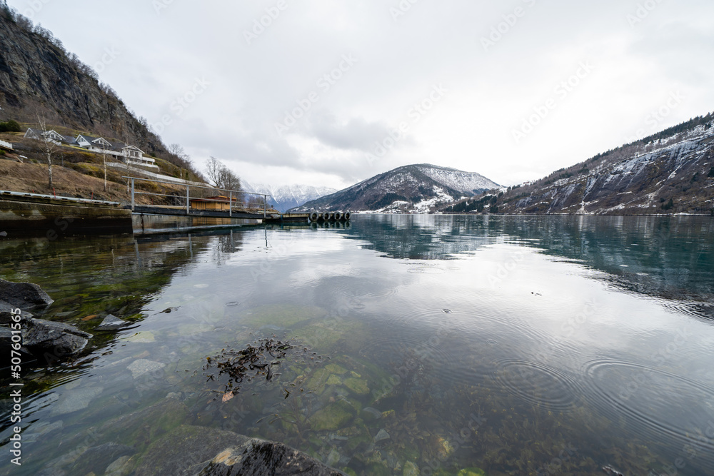 Obraz premium Norwegian fjord in early spring when there is still snow in the mountains and the water is calm like a mirror