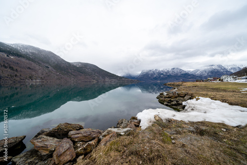 Norwegian fjord in early spring when a little snow on the shore and blue-green water is like a mirror