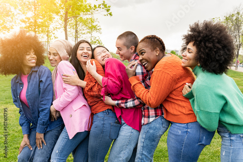 Happy multiracial women having fun together - Multiracial friends smiling at camera outdoors - hugging, happy life travel and friendship concept.