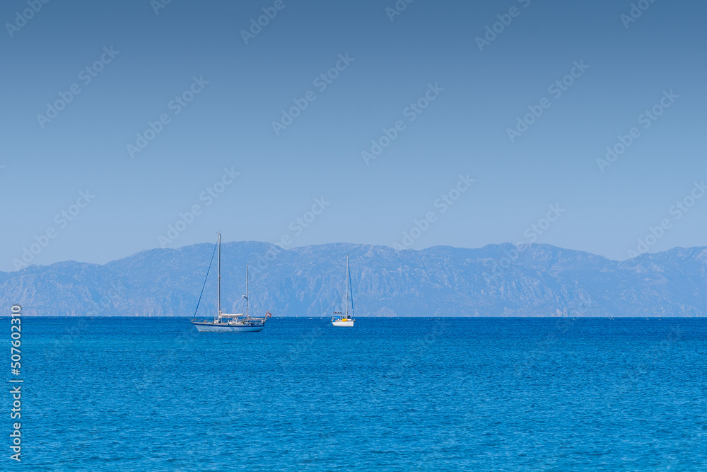 Tow sailing boats in ocean,in the background mountains.