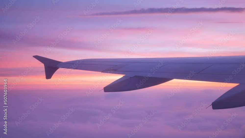 Airplane wing above the clouds at scenic pink and lilac sunset. 4K, Handheld. Contains audio Airplane wing above the clouds at scenic pink and lilac sunset. 4K, Handheld. Contains audio