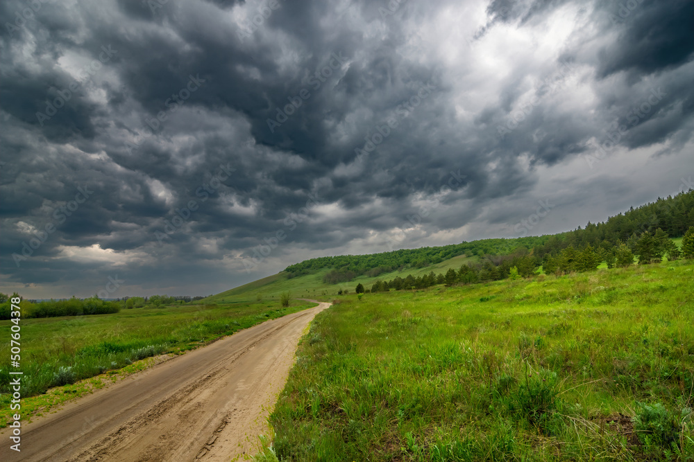 dirty road way under Humidity dramatic sky between green hills to mountains summer scenery landscape