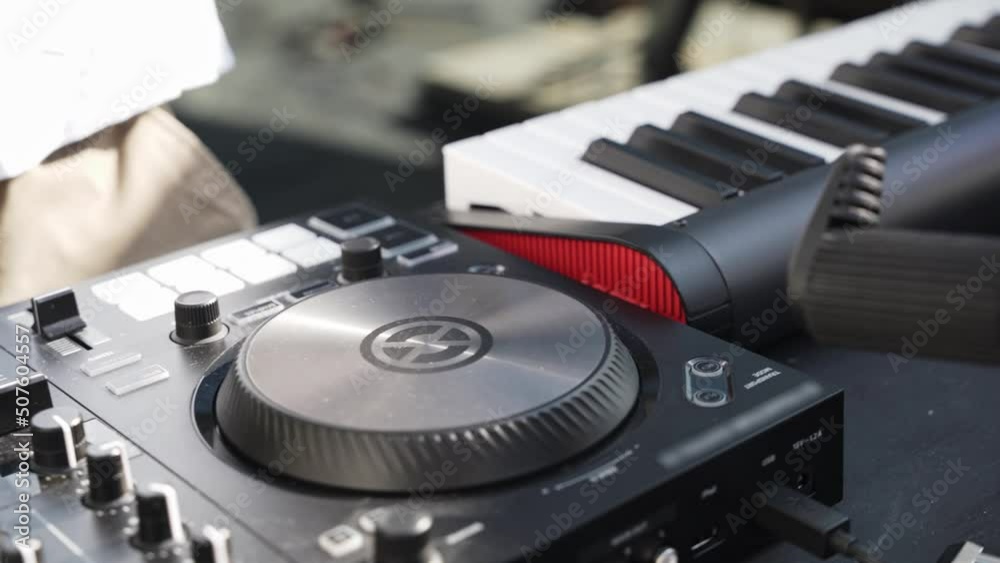 A close-up of a man in a white car wash walks up to the DJ remote on which the headphones lie and picks up from hand to wear to a concert or rehearsal outside. A close-up of a man in a white car wash walks up to the DJ remote on which the headphones lie and picks up from hand to wear to a concert or rehearsal outside.