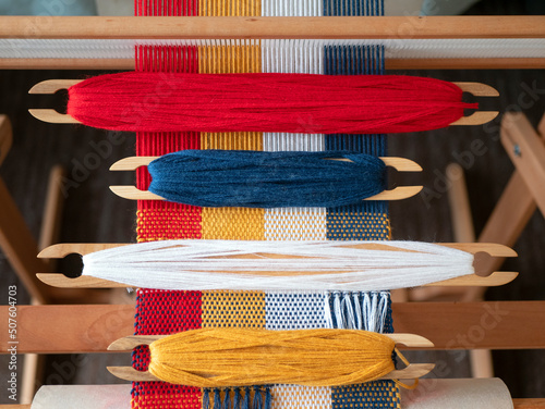 Four shuttles with yarn of different colors on the loom. Weaving shuttles with colored threads on the weaving project photo