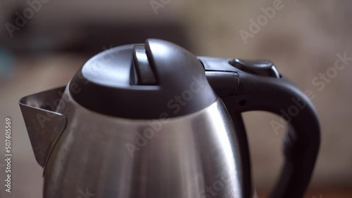 Button for turning on the electric kettle for boiling water. An electric kettle boils water. Person turns on the electric kettle. photo