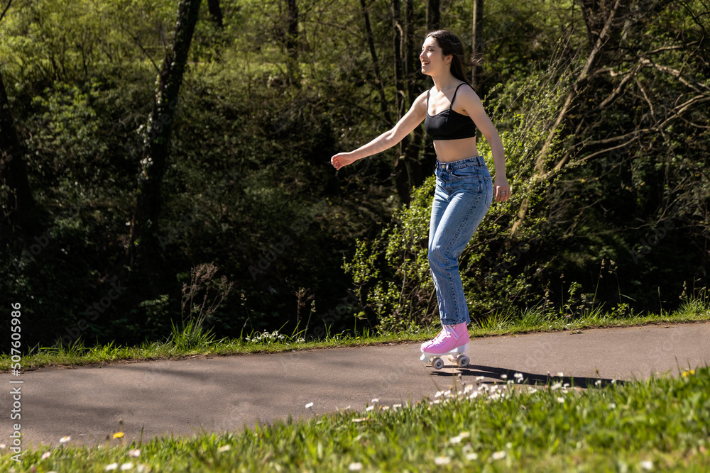brunette woman skating in the park with pink roller skates