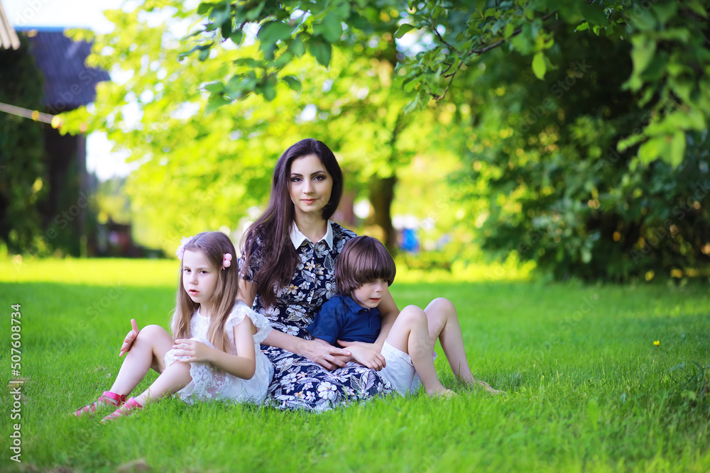 Young large family on a summer morning walk. Beautiful mother with children is playing in the park. Young large family on a summer morning walk. Beautiful mother with children is playing in the park.