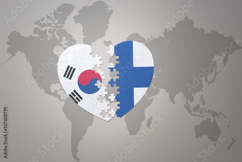 puzzle heart with the national flag of finland and south korea on a world map background. Concept.