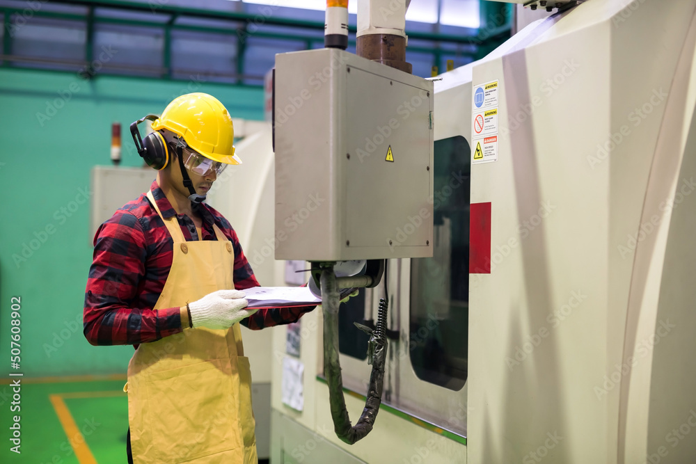 Factory worker check manual paper to command CNC panel