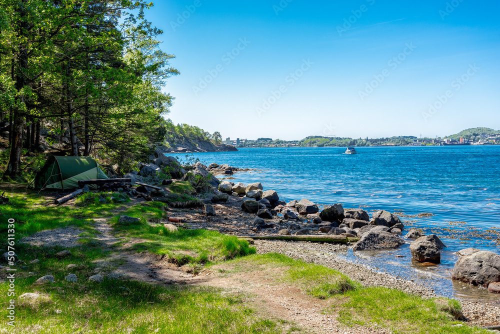 A camping tent set up on a rocky coast of Gandsfjord fjord near Dale and treks to Lifjel mountain, Sandnes, Norway, May 2018