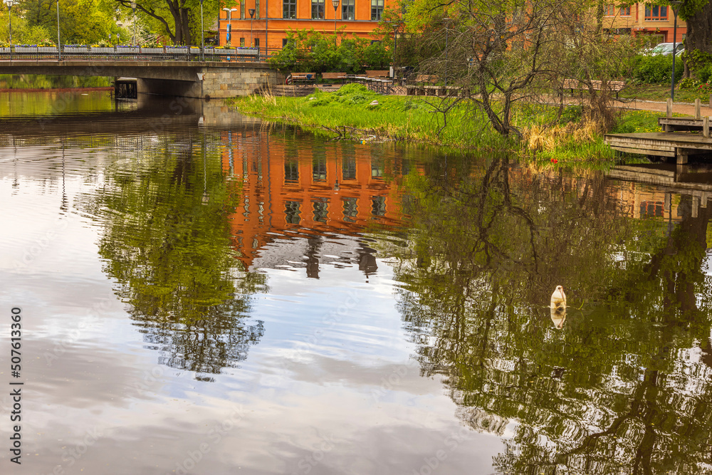 Beautiful view of reflection of city's houses in clear calm mirror water on warm summer day. Sweden.