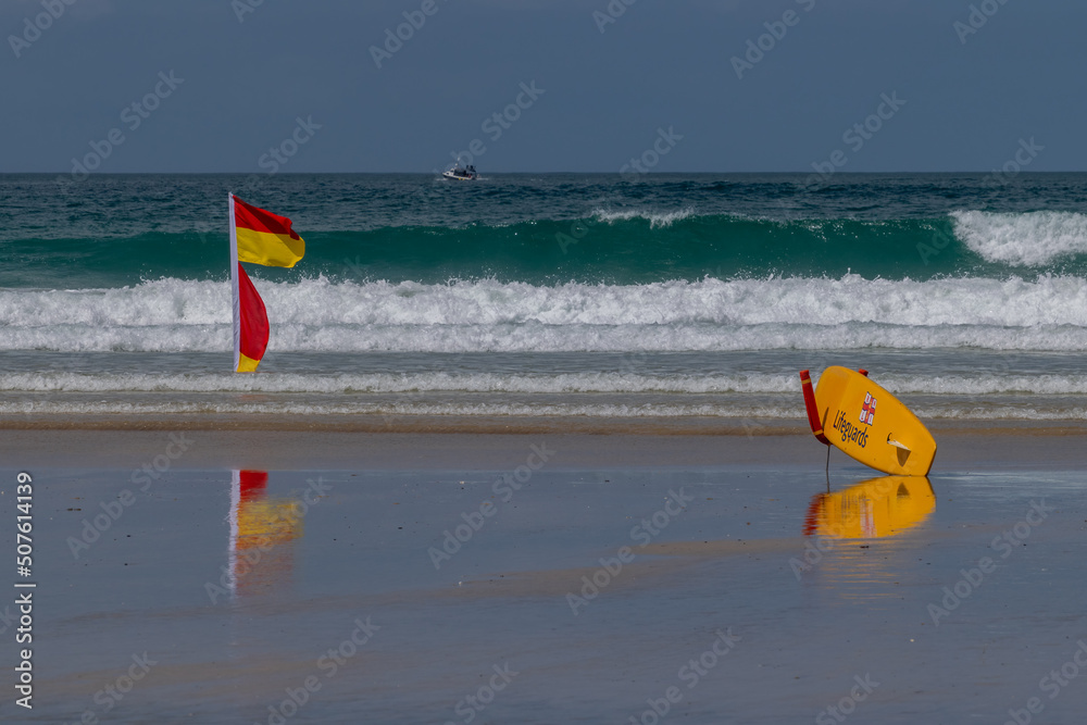 Lifeguard paddleboard and red and yellow warning flag