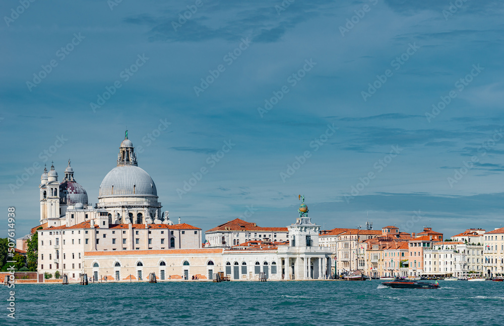 Panoramic view over Grand Canal with Basilica di Santa Maria della Salute, in Venice historical downtown, Italy, at sunny warm day and blue sky.