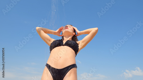 Bottom view of a wet woman in a black swimsuit. Portrait of a woman under the shower