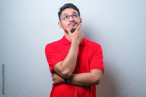 Young asian man thinking worried about a question, concerned and nervous with hand on chin