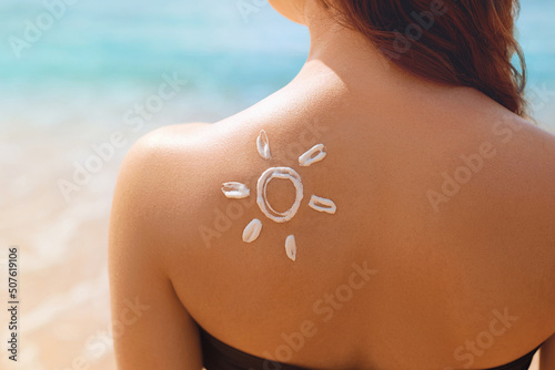 Beautiful Woman In Bikini apply sun cream on Face. Woman With Suntan Lotion On Beach. Portrait Of Female Holding Moisturizing Sunblock