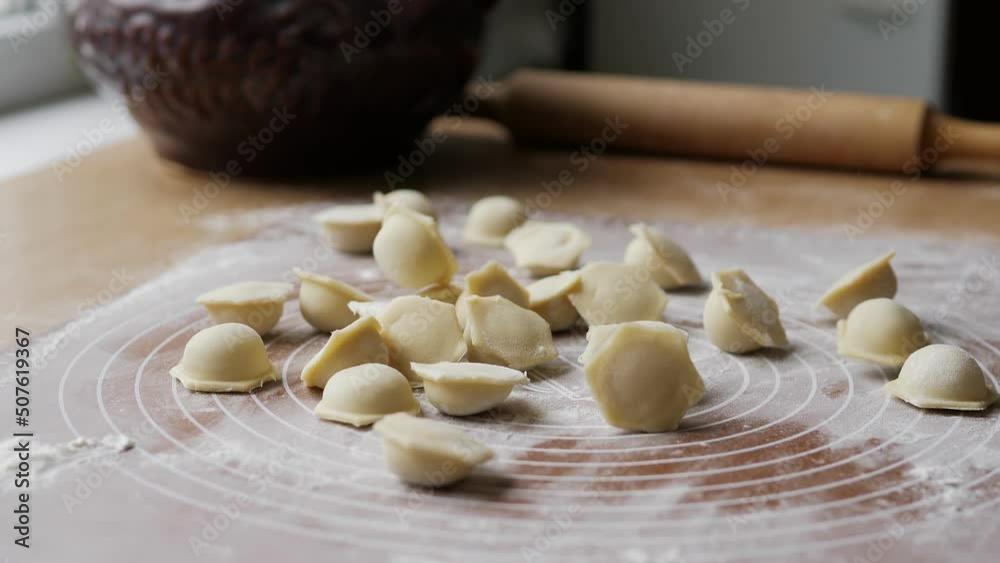 Close-up of raw homemade Russian fresh dumplings crumbling on the table. Freshly molded dumplings are poured out of the mold. A traditional Russian dish is dumplings with meat filling. Close-up of raw homemade Russian fresh dumplings crumbling on the table. Freshly molded dumplings are poured out of the mold. A traditional Russian dish is dumplings with meat filling.