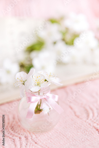 Open old book with white small flowers on a pink background 