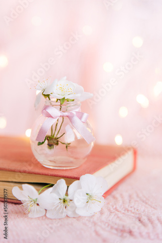 Open old book with white small flowers on a pink background 
