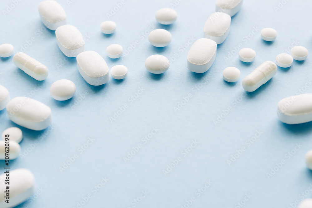 
White pills on a pastel blue background. Capsules and round pills close-up. health care and medicine.