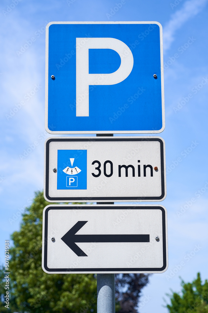 Signs with the information that cars with a parking disc can park for 30 minutes. There is a sign with an arrow pointing to the left. Three individual traffic signs. Signs with the information that cars with a parking disc can park for 30 minutes. There is a sign with an arrow pointing to the left. Three individual traffic signs.