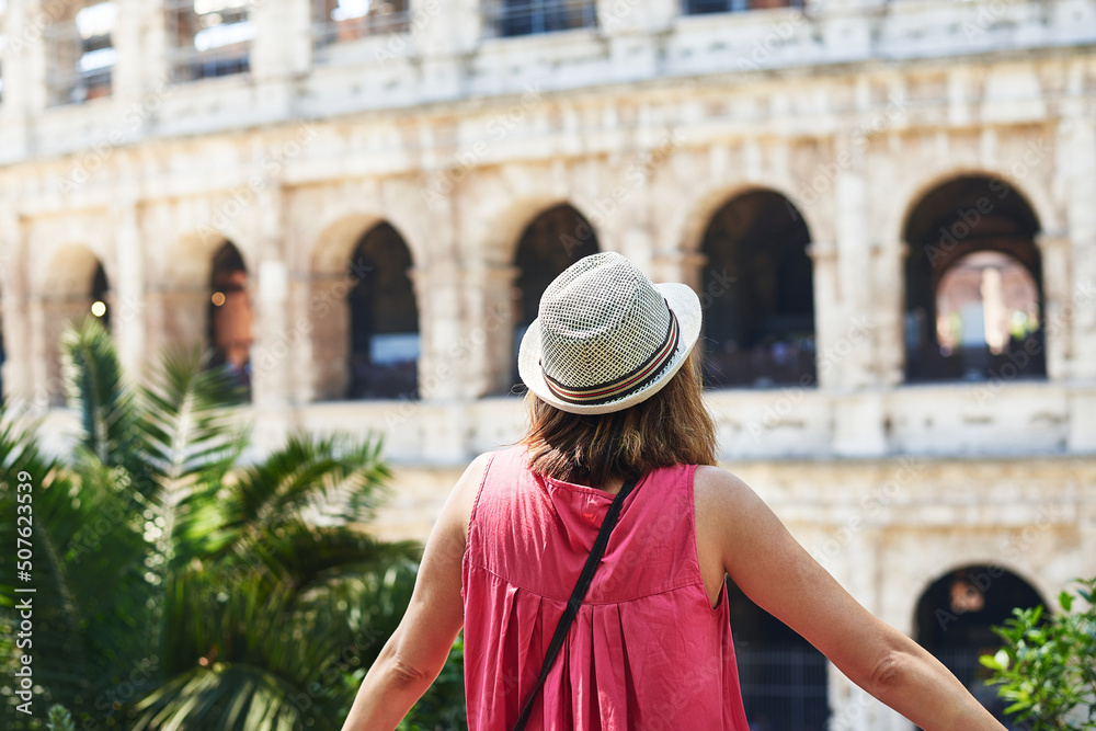 Woman tourist in Rome. Woman tourist in red dress and hat visiting Rome observing Colosseum.