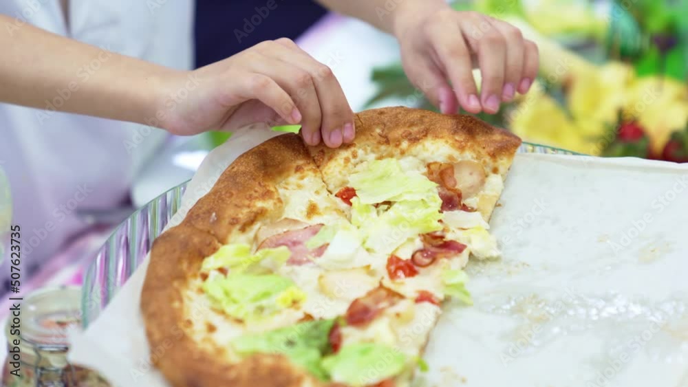 children's hands tear off a slice of pizza. traditional treat for a children. children's hands tear off a slice of pizza. traditional treat for a children.