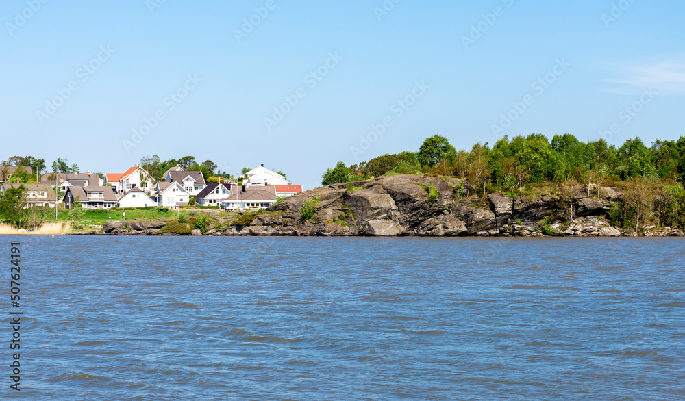 Rocky hill and residential houses along the coast of Halandsvatnet lake, Stavanger, Norway, May 2018