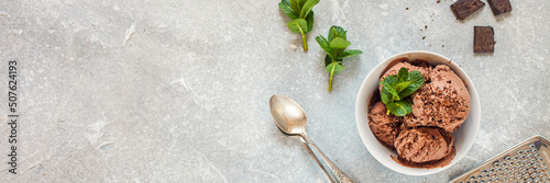 Chocolate ice cream with a bowl on a table. Ice cream, chocolate, cocoa, mint, grater. Summer dessert. Selective focus. Copy space. Flat lay.