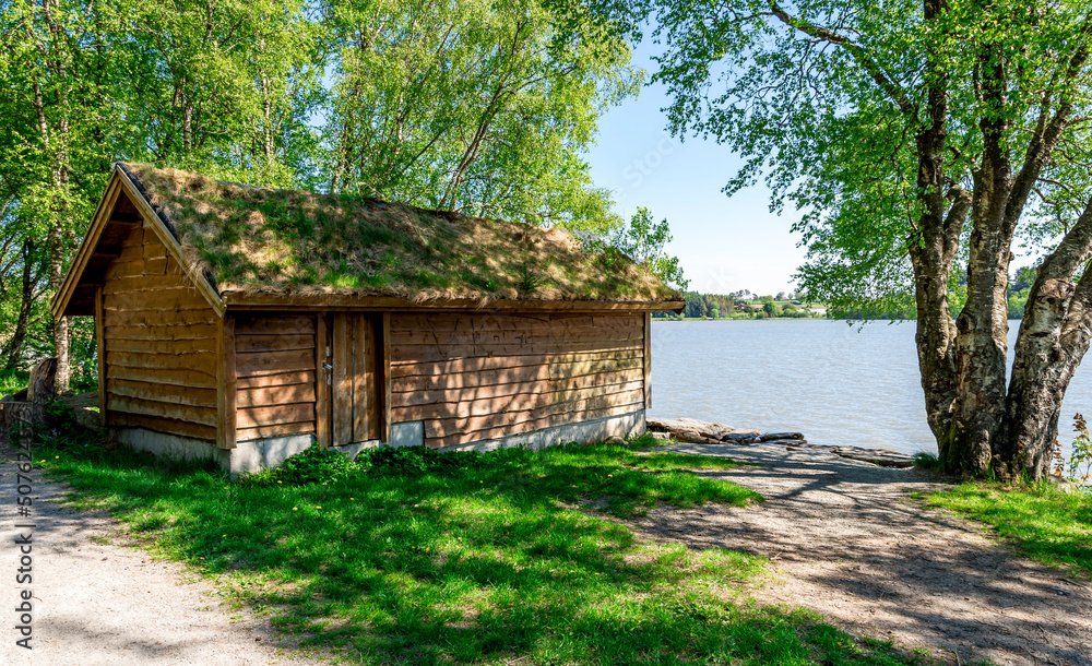 A wooden hut with traditional grass covered roof on shores of Halandsvatnet lake, Stavanger, Norway, May 2018