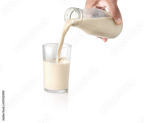 Milk pouring into the clear glass isolated on white background