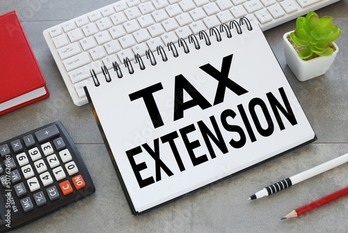 TAX EXTENSION. text on an open notepad on a gray background. calculator. notebook.