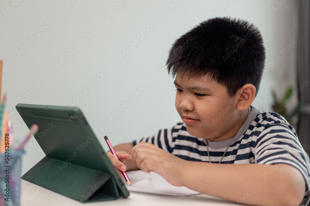 Cute Asian child learning class study online with video call from tablet at home .Social distancing concept Cute Asian child learning class study online with video call from tablet at home .Social distancing concept