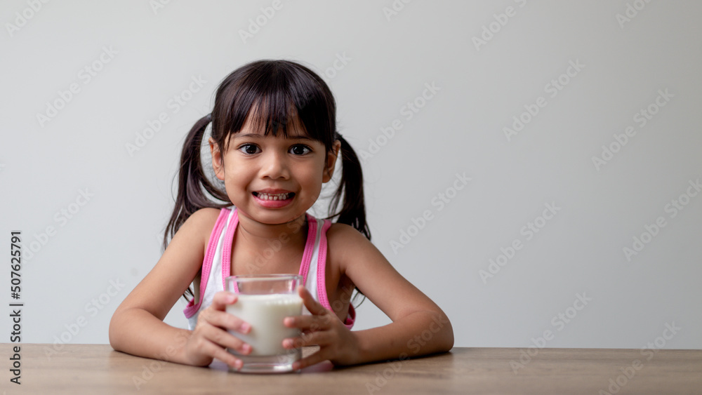 Asian little girl is drinking milk from a glass she was very happy. Asian little girl is drinking milk from a glass she was very happy.