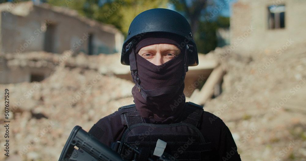 A soldier in the background of a destroyed building turns his head, looks in front and raises his rifle. A soldier in the background of a destroyed building turns his head, looks in front and raises his rifle.