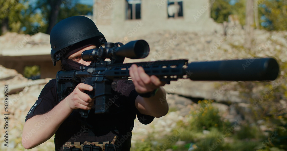 Fototapeta premium The soldier raises his rifle, aims and fires a shot.