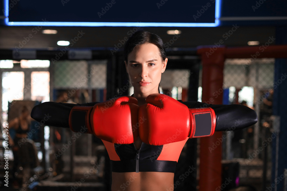 Young sports woman in tracksuit and putting hands together in red boxing gloves.