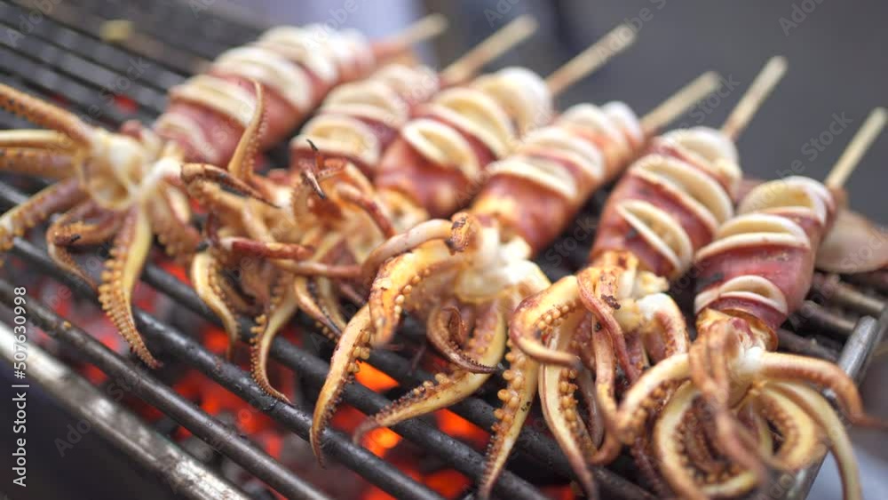 Squid barbecue grilling on the charcoal fire wood. Street food in Bangkok footage in 4K.
