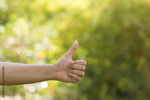 Hands,women with thumbs up sign on bokeh background in public park.